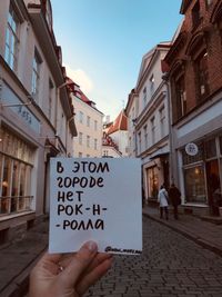 Low section of person holding text on street against buildings in city