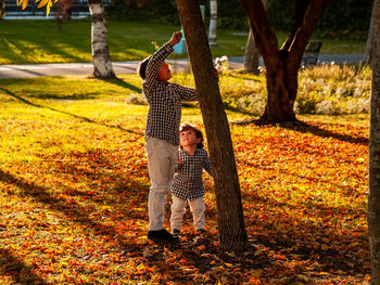 Siblings playing in park during autumn