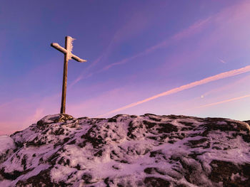 Low angle view of cross on mountain against sky
