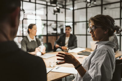 Mid adult female entrepreneur discussing with colleague in board room