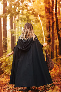 Rear view of woman standing in forest during autumn