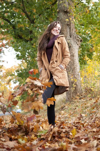 Low angle view of woman kicking fallen autumn leaves at park