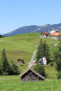 Built structure on field by houses against clear sky