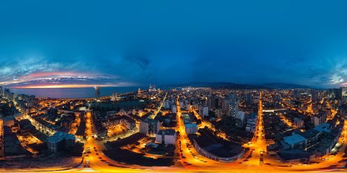 High angle view of illuminated cityscape against blue sky