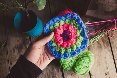 Close-up of hand holding multi colored wool on table