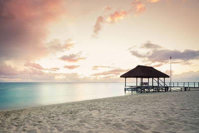 Lifeguard hut on beach against sky during sunset