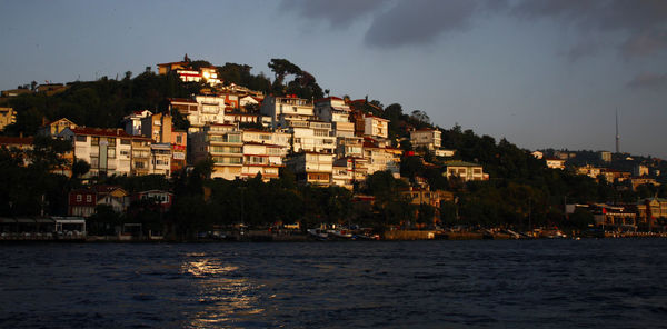 Buildings by sea against sky at night