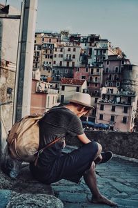 Man sitting against buildings in city