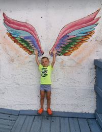 Full length portrait of boy standing against wall