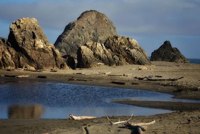 Rocks on shore by sea against sky