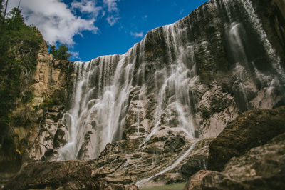 Low angle view of waterfall against sky