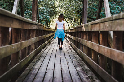 Rear view of woman walking on footbridge