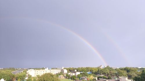 Rainbow over buildings in city against sky