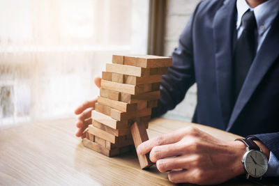 Midsection of businessman stacking dominoes at table