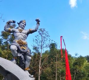 Low angle view of angel statue against trees