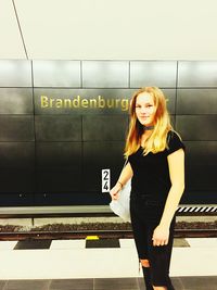 Portrait of smiling woman standing at railroad station