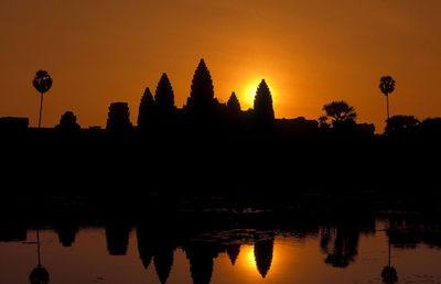 Silhouette angkor wat in front of lake during sunset