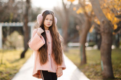 Cute kid girl 10-12 year old with long blonde hair wear fluffy headband earphones and pink jacket