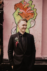 Young man standing against wall