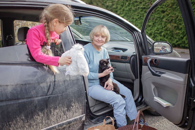 Low angle view of young woman standing by car