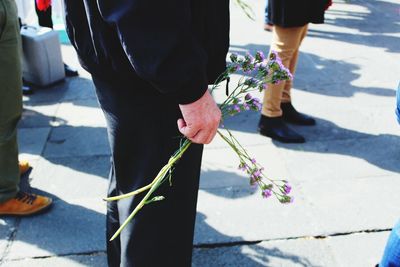 Low section of man holding flower on street