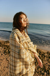 Portrait of young woman standing against sea against sky