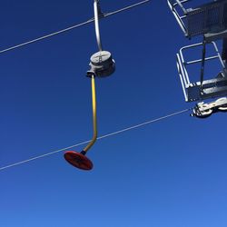 Low angle view of telephone pole against clear blue sky