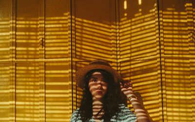 Portrait of young woman standing against door