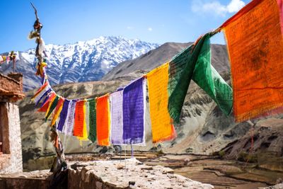 Multi colored flags hanging on mountain against sky