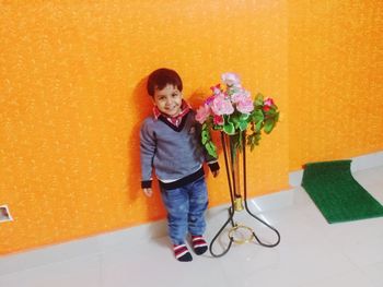 Portrait of smiling girl standing against orange wall