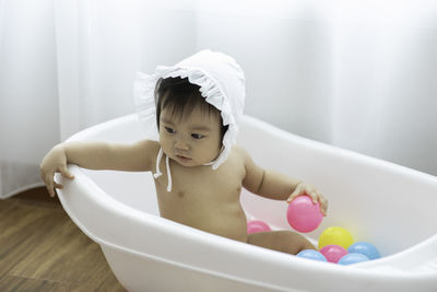 Cute baby girl holding ball in bathtub
