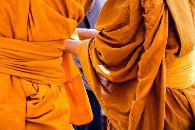 Midsection of monks wearing traditional clothing while standing outdoors