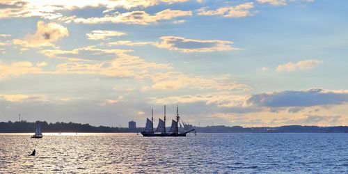 Sailboats sailing on sea against sky during sunset