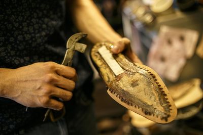 Midsection of shoemaker holding sole of shoe