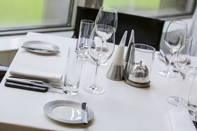 High angle view of wineglasses with plates and cutlery arranged on dining table at restaurant