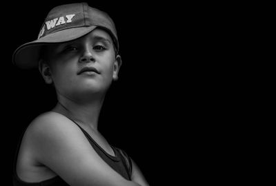 Portrait of boy standing against black background