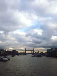 Boats in river against cloudy sky