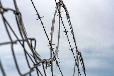 Low angle view of barbed wire against sky