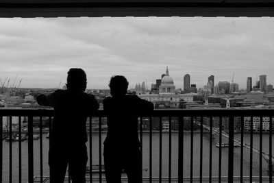 Silhouette of two people looking at city buildings