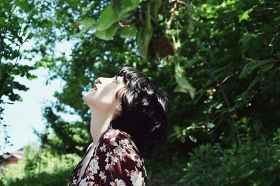 Side view of woman standing against trees