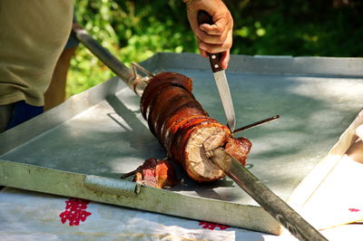 Cropped shot of hands cutting big piece of pork meat on the table in nature