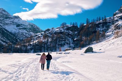 Rear view of two people walking on snow covered mountain