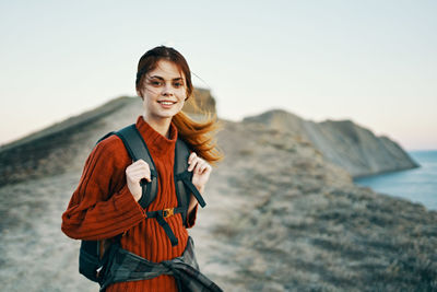 Portrait of smiling young woman standing against sky