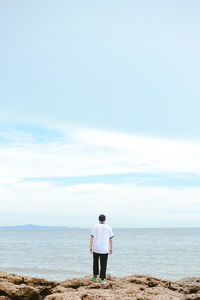 Rear view of man standing on beach against sky