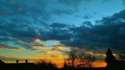 Low angle view of silhouette trees against cloudy sky