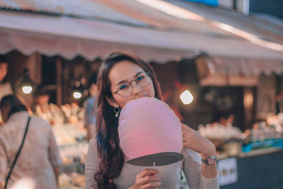 Portrait of woman holding cotton candy at market