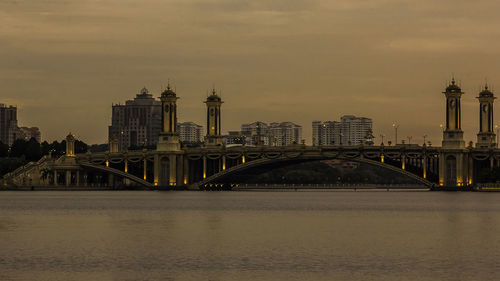 Bridge over river with buildings in background at sunset