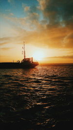 Silhouette ship in sea against sunset sky