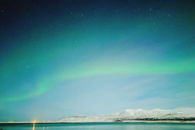 Scenic view of sea against rainbow in sky at night