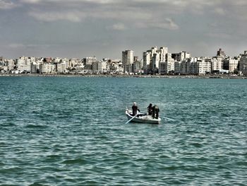 Boats in sea with city in background